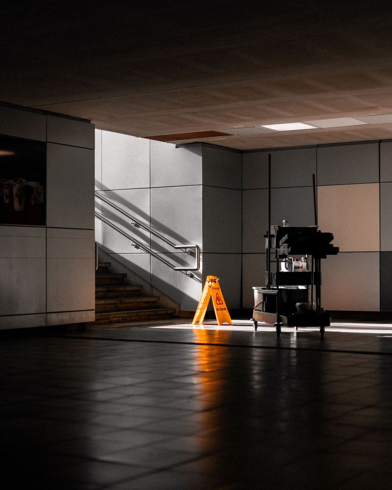 Cleaning equipment and a wet-floor sign in a building corridor